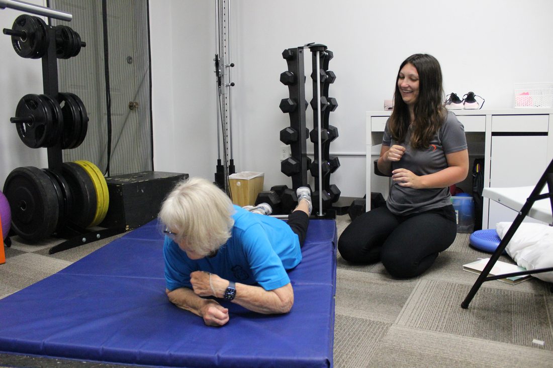 Kinesiologist Cambrie coaching an older client through a core exercise at Jannalee Physiotherapy
