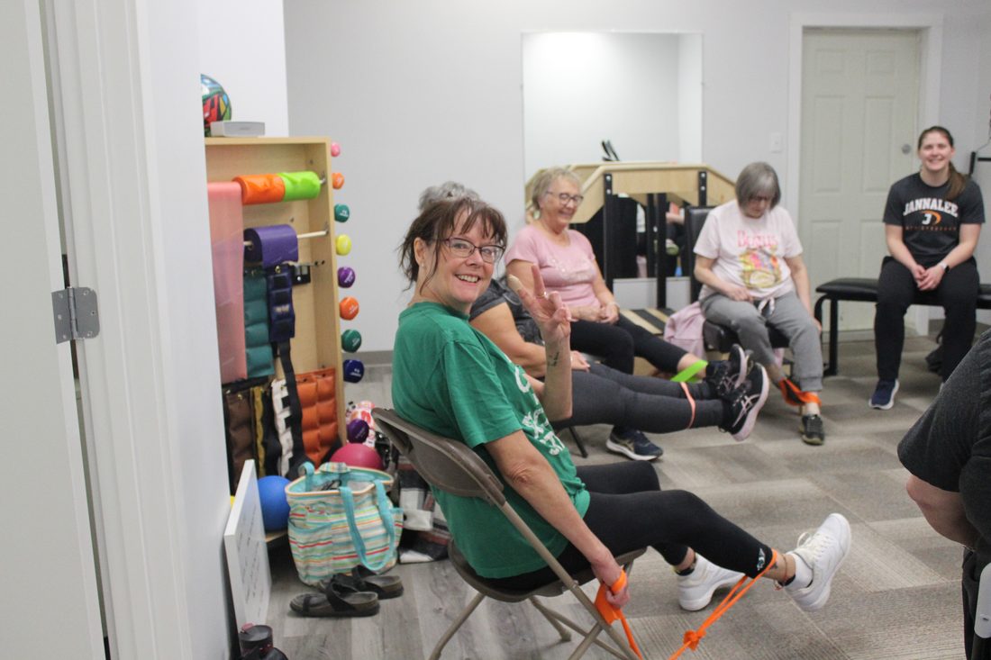 Adults exercising with resistance bands in a seated group class at Jannalee Physiotherapy