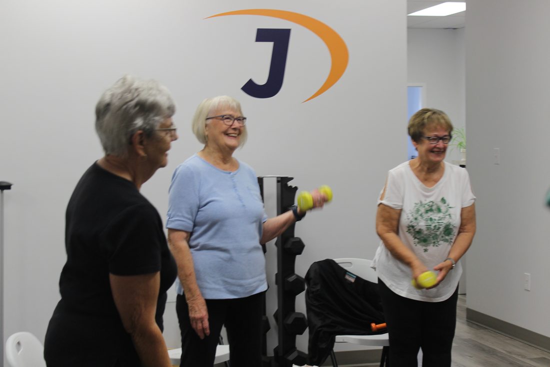Older adults laughing together during a group exercise class with light weights at Jannalee Physiotherapy