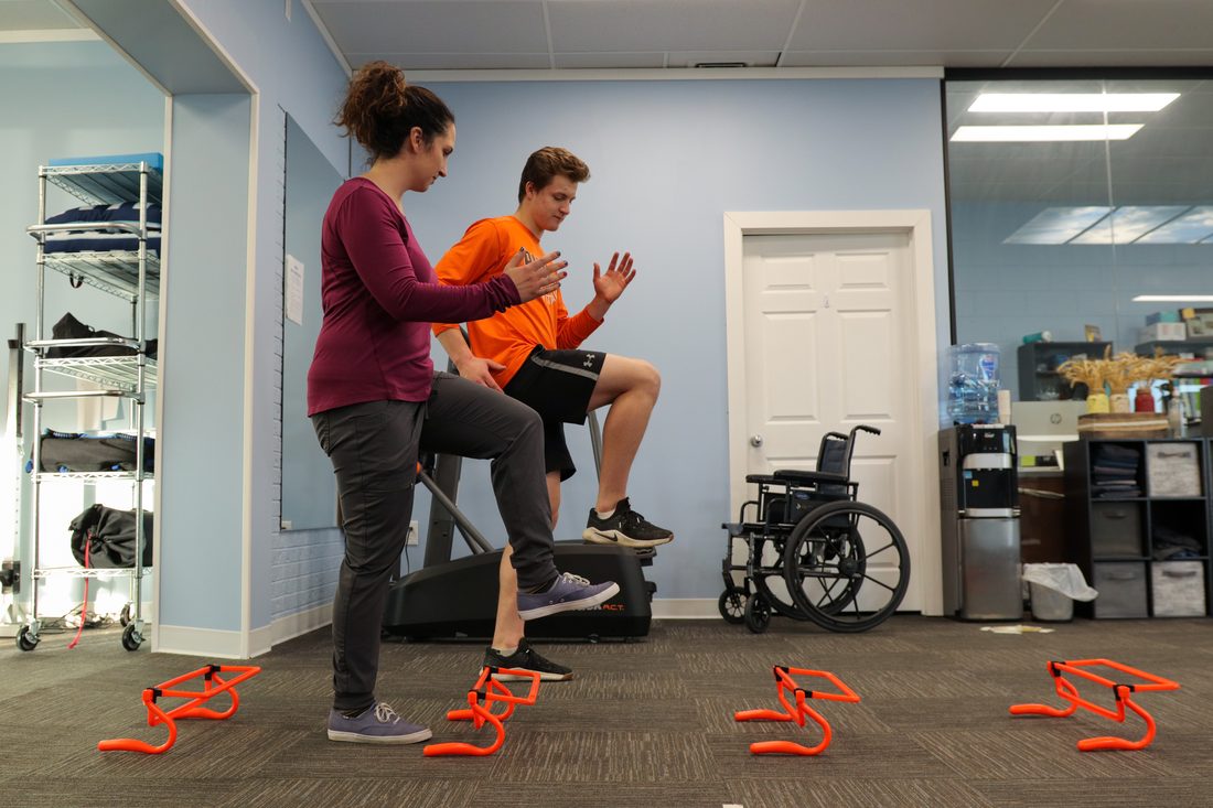 Physiotherapist guiding a patient through a step-up exercise to build knee strength