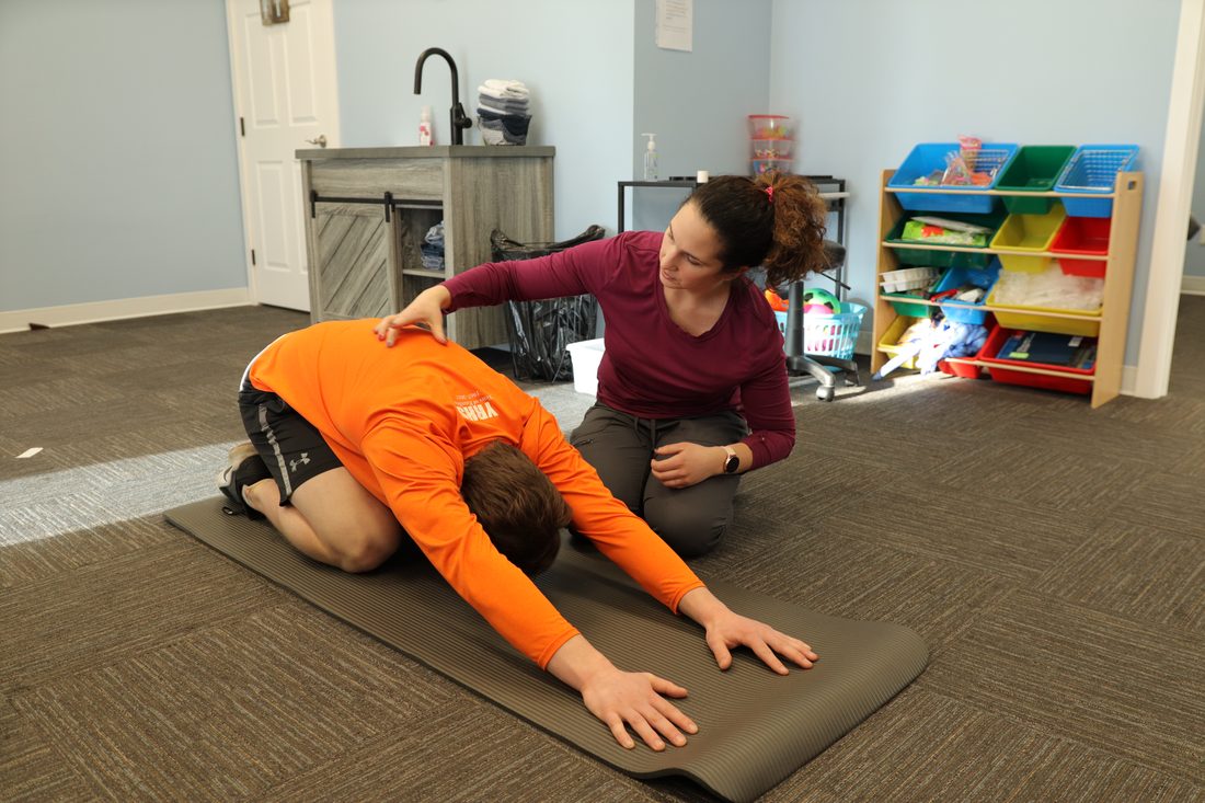 Physiotherapist guiding a patient through a low-back mobility stretch